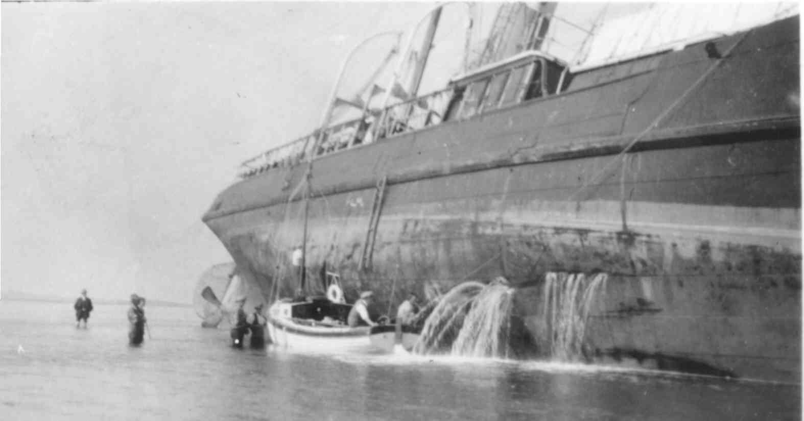 Albert Barnes and Harold Benest inspect the damage from the Diana while water gushes out the the hull of the stricken vessel